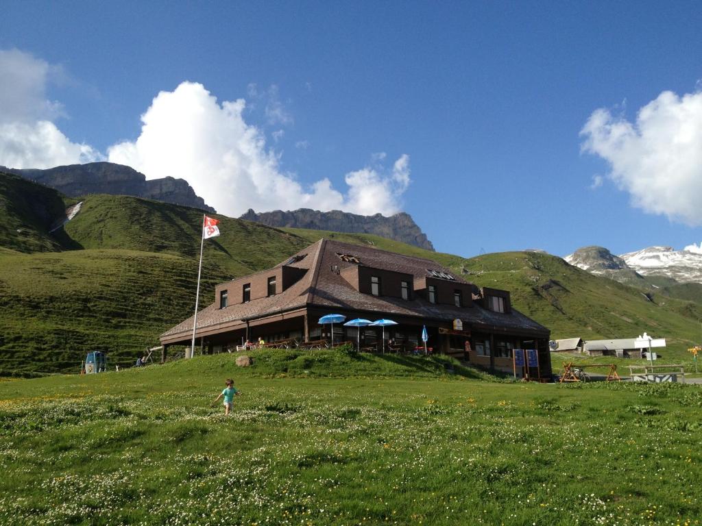 ein Gebäude auf einem Hügel mit einem Kind auf einem Feld in der Unterkunft Berggasthaus Tannalp in Frutt