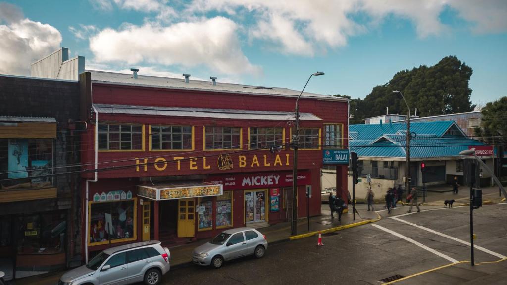 2 auto sono parcheggiate di fronte a un edificio di Hotel Balai ad Ancud