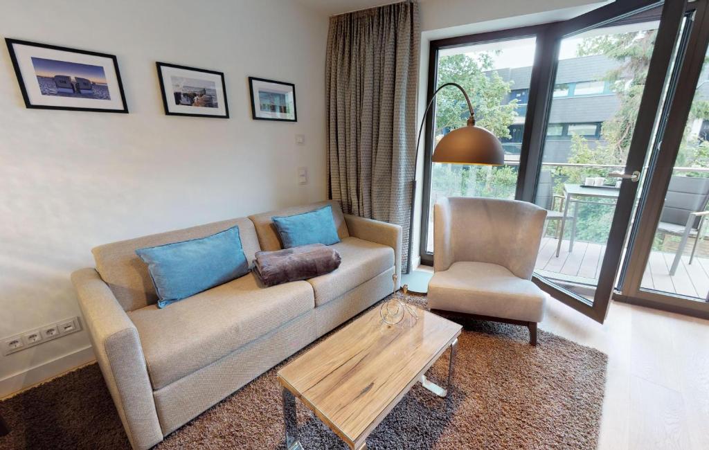 sala de estar con sofá y silla en White Pearl Apartment 1.02, en Timmendorfer Strand