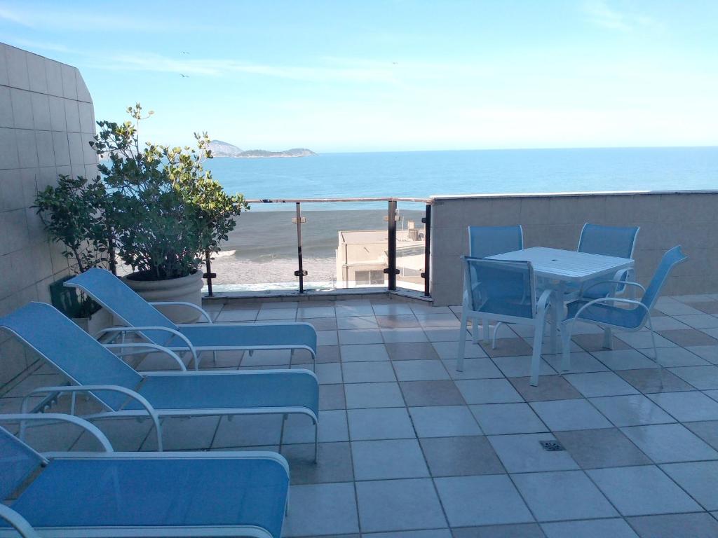 a patio with blue chairs and a table and the beach at Apartamento Ipanema in Rio de Janeiro