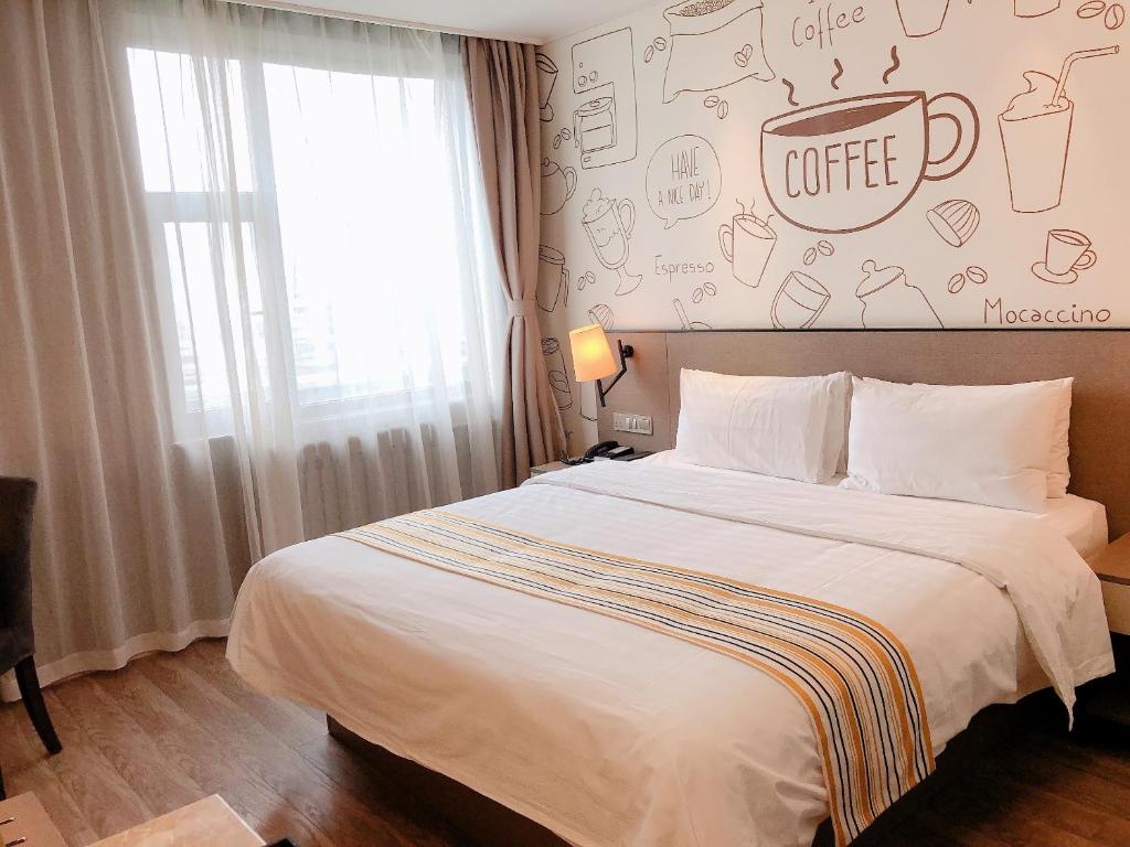 a bedroom with a large bed with a coffee sign on the wall at Home Inn Plus Lanzhou Zhangye Road Pedestrain Street in Lanzhou