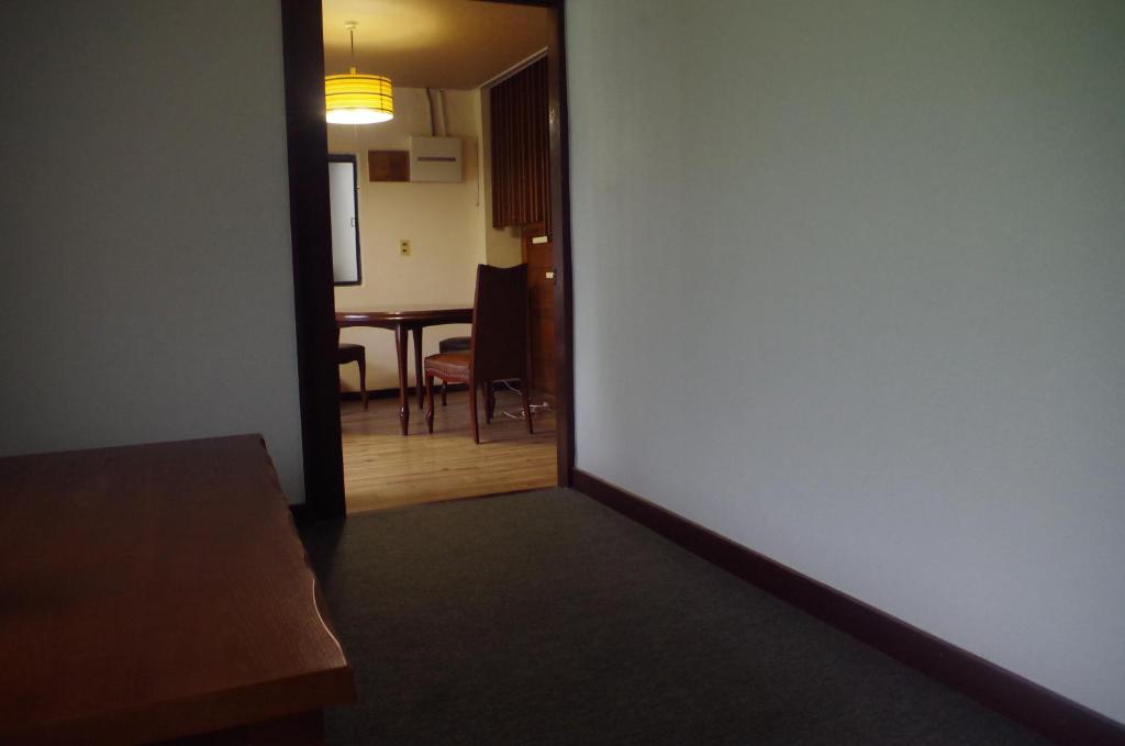 a room with a hallway with a table and a room with a wall at Kusatsu Onsen Guesthouse Gyoten in Kusatsu