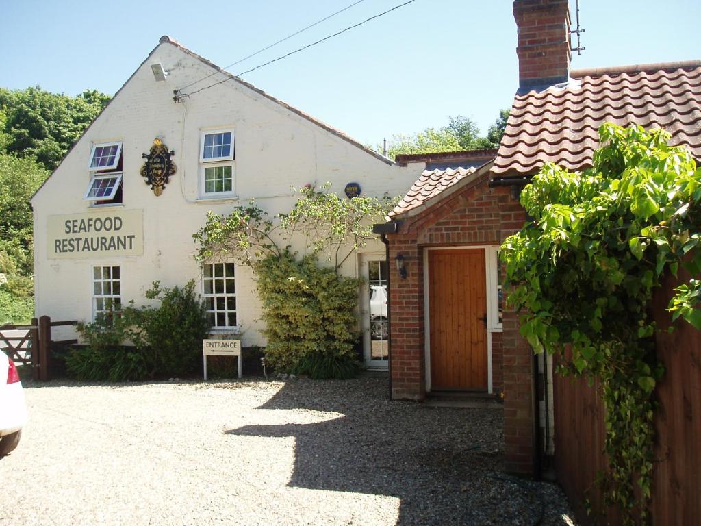 un edificio blanco con una puerta delante en The Old Forge Seafood Restaurant and Bed and Breakfast, en Thursford