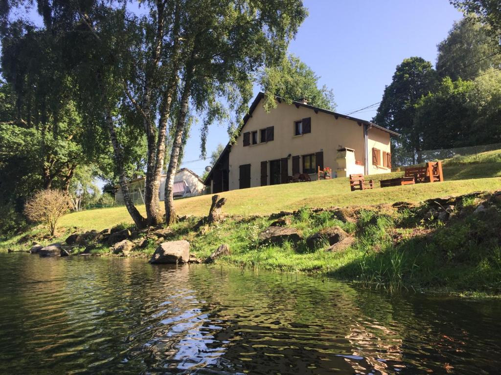 a house sitting on top of a hill next to a river at Maison Lac de Pareloup -LES PIEDS DANS L'EAU- in Arvieu