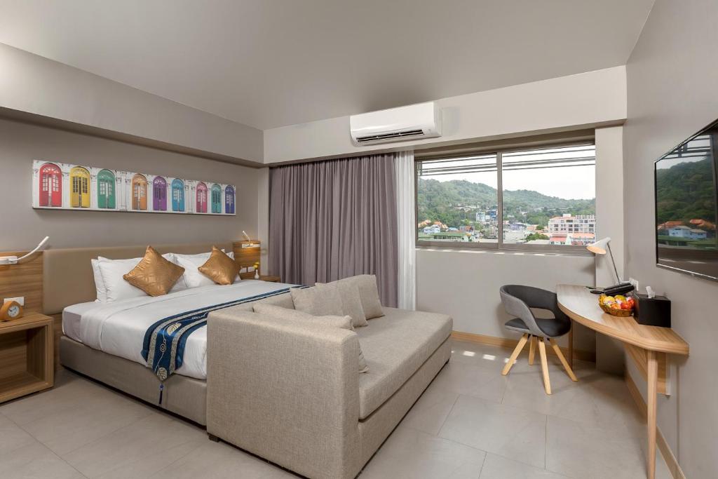 a bedroom with a bed and a desk and a chair at Journeyhub Phuket Patong in Patong Beach