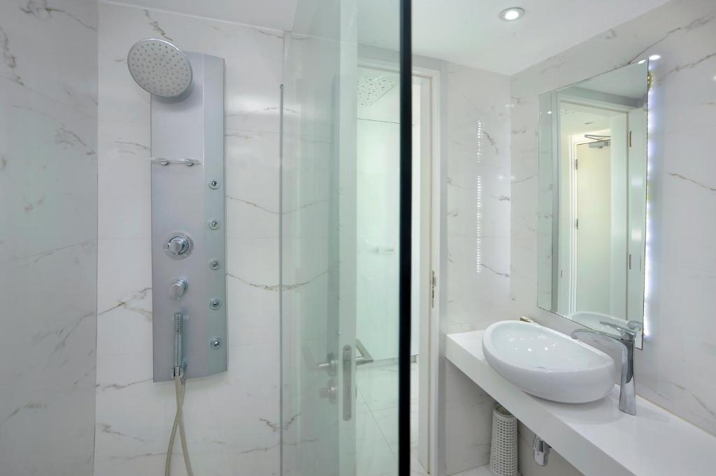 a white bathroom with a sink and a shower at Nestor Hotel in Ayia Napa