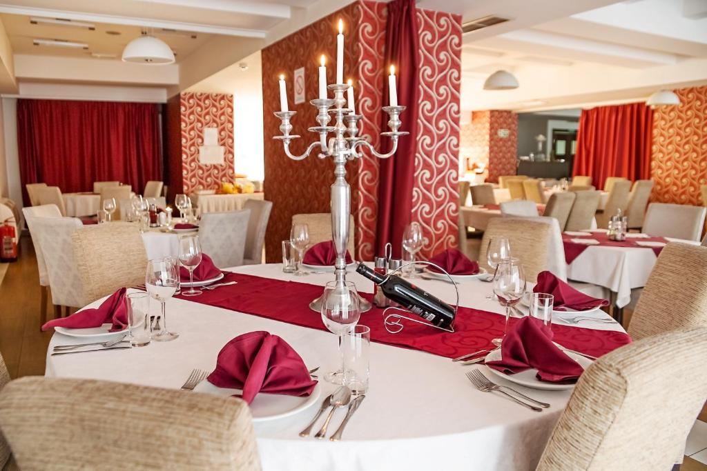 una sala da pranzo con tavoli bianchi e tovaglioli rossi di Hotel Putnik a Novi Sad