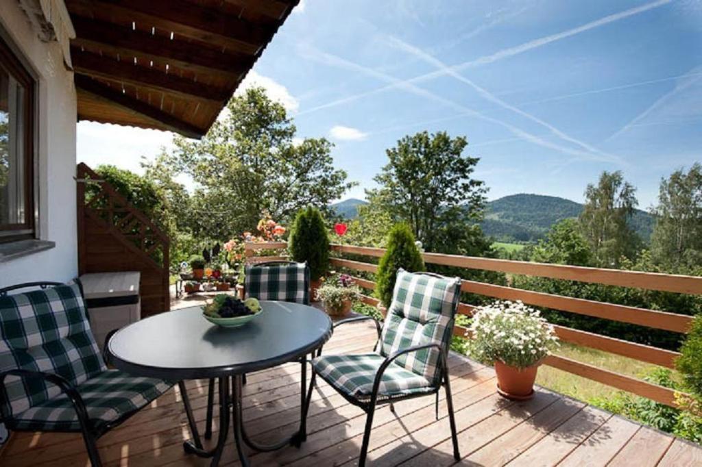 a patio with a table and chairs on a wooden deck at Ferienwohnung-Panoramablick-1 in Bodenmais