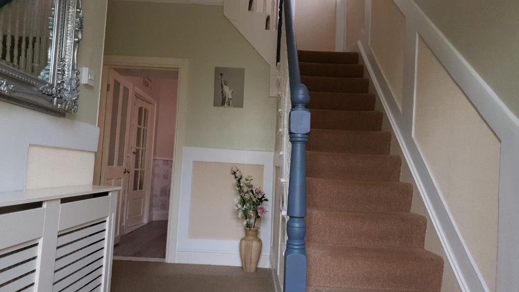 uma escada numa casa com um vaso de flores em Grandeur Holiday home, with free parking em Clacton-on-Sea