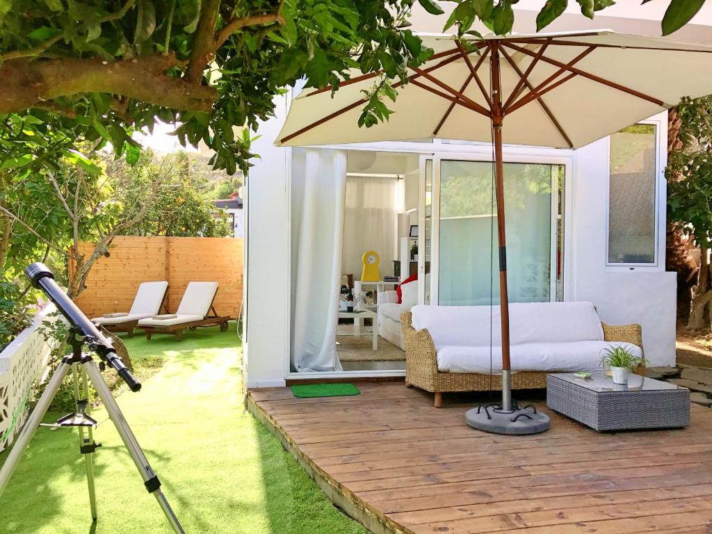 an umbrella on a wooden deck with a bedroom at Flatguest - Glass House in Santa Brígida