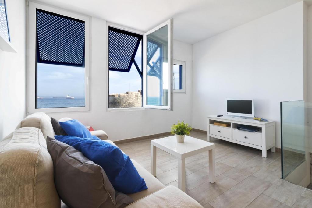 sala de estar con sofá, TV y ventanas en Flatguest - Castle Sea View, en Las Palmas de Gran Canaria