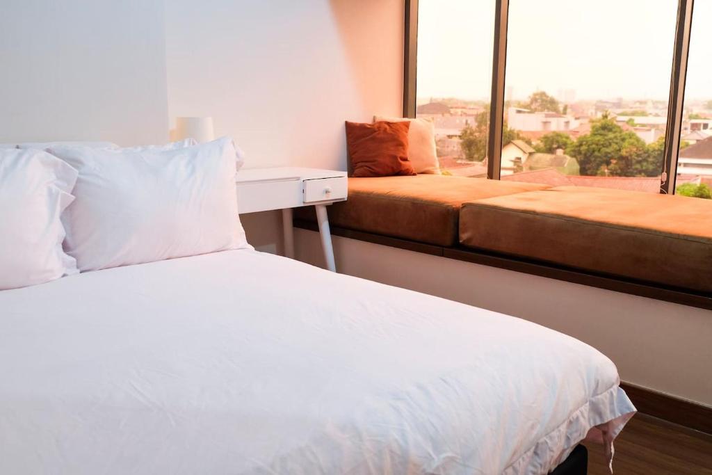 a bedroom with a white bed and a large window at Lavenderbnb 1 at Uttara The Icon Apartment in Yogyakarta