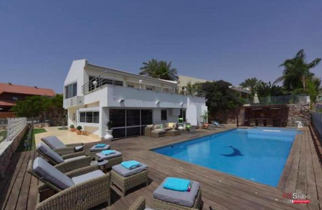 a house with a swimming pool in front of a house at Villa with heated pool and Jacuzzi Sea View 300m Front of the Beach in Eilat