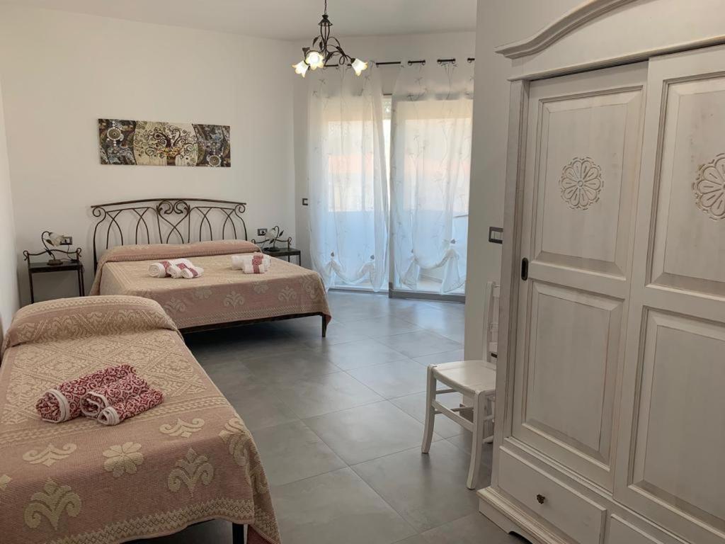 a bedroom with two beds and a sliding door at B&B Centrale in Tortolì
