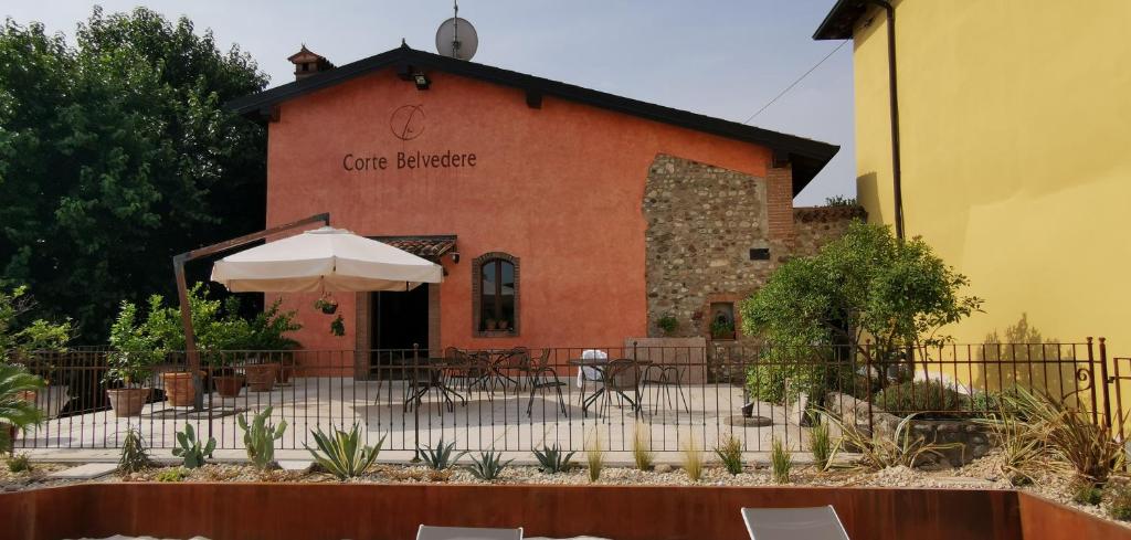 un bâtiment avec une table et un parasol devant lui dans l'établissement Corte Belvedere, à Custoza