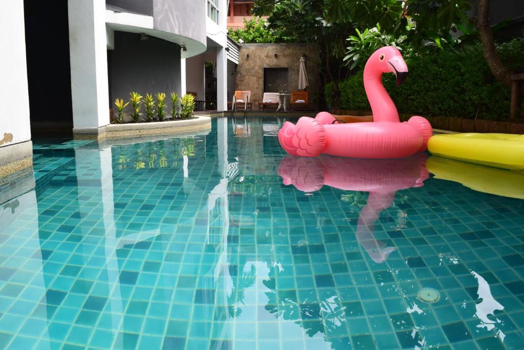 A tiled courtyard pool contains a pink flamingo float and a yellow inflatable.