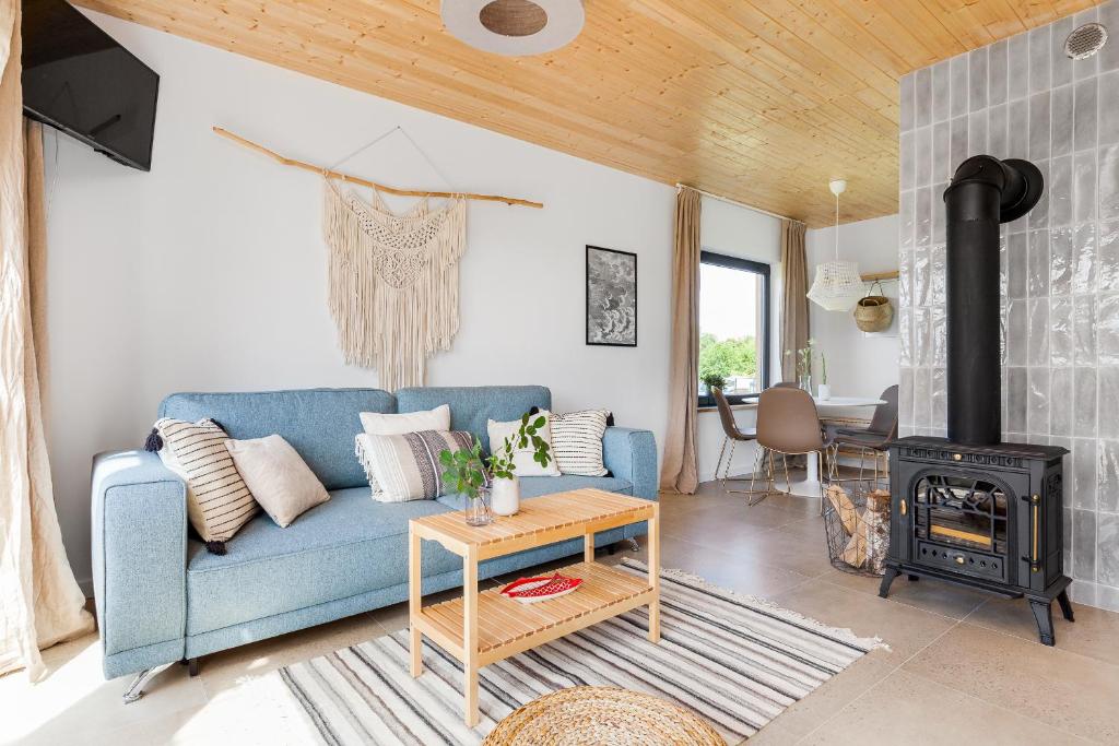 a living room with a blue couch and a wood stove at Domki ROSSE niedaleko plaży in Jastrzębia Góra