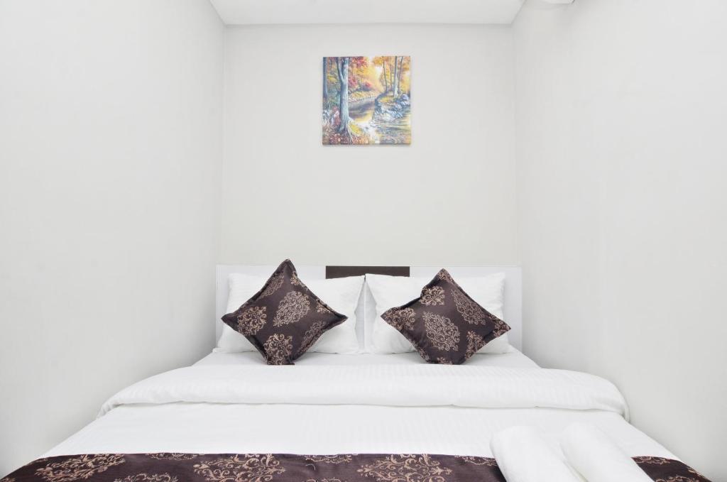 a bedroom with a white bed with black pillows at K VILA HOTEL in Sungai Petani