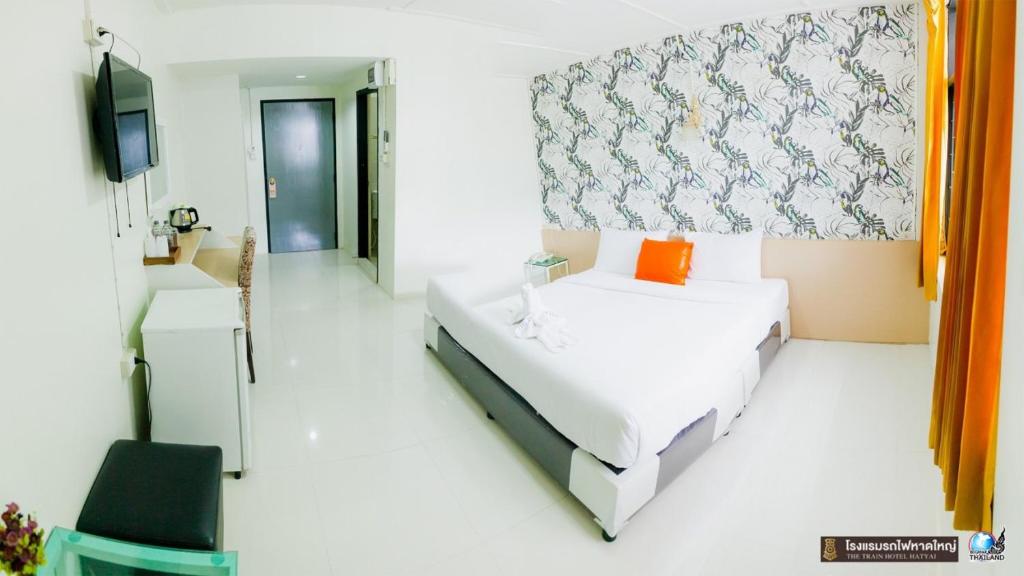a white room with a bed and a tv at The Train Hotel Hatyai in Hat Yai