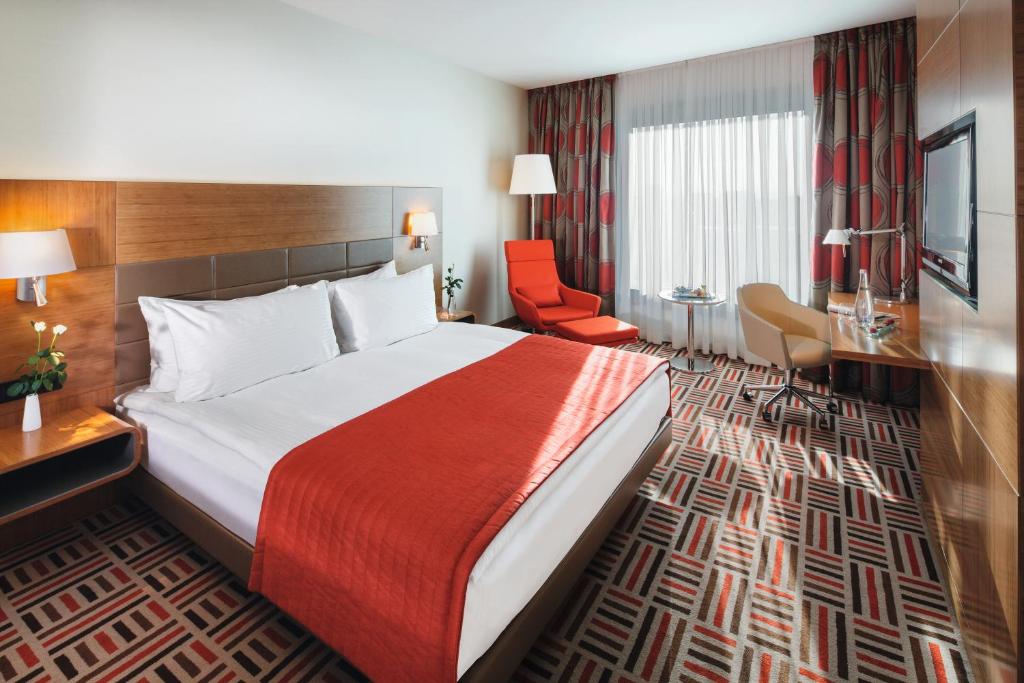 a hotel room with a large bed and a chair at Movenpick Hotel Ankara in Ankara