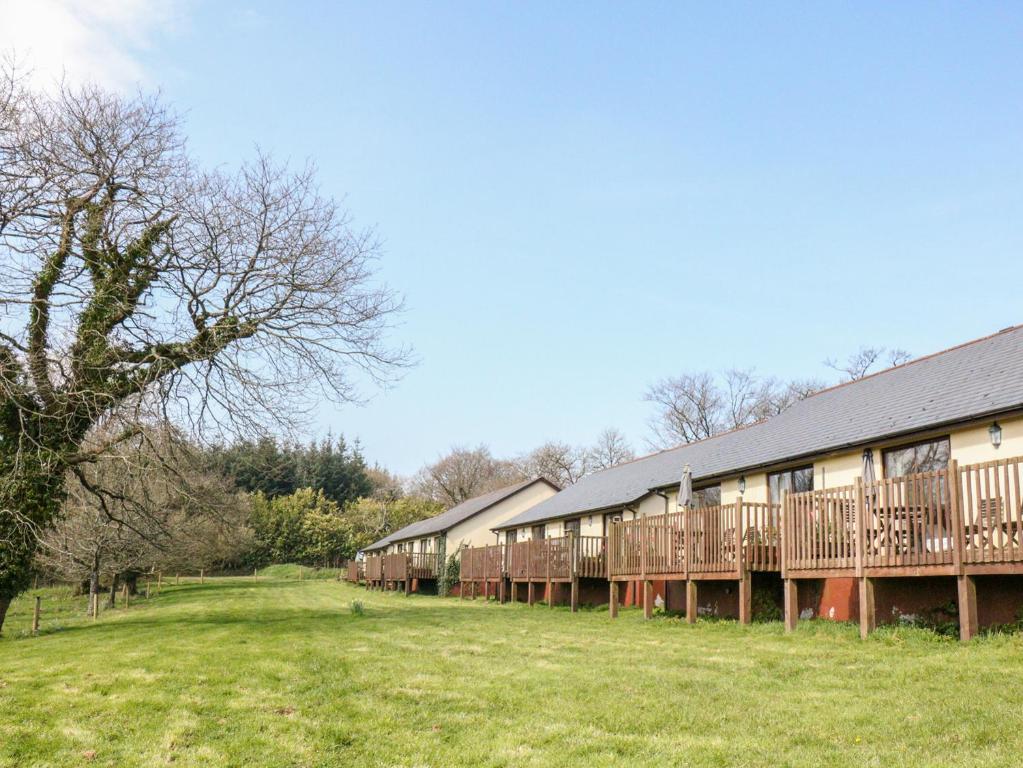 a row of buildings with a field and trees at Mallard in Beaworthy