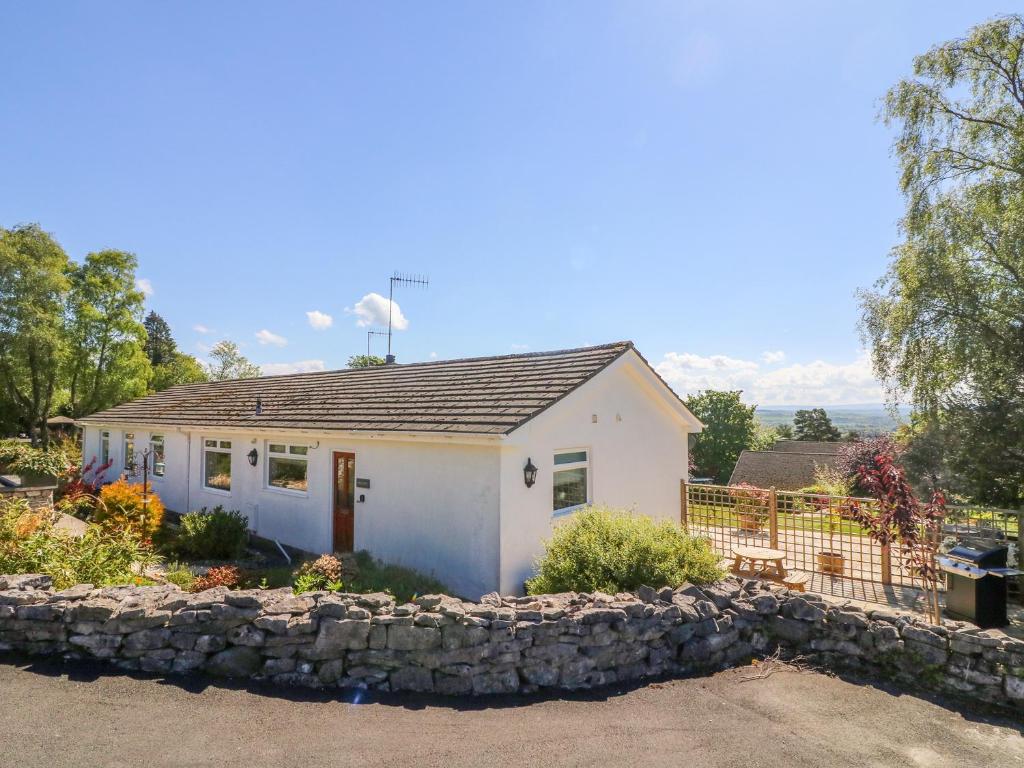 a small white house with a stone wall at Moss Cote in Milnthorpe