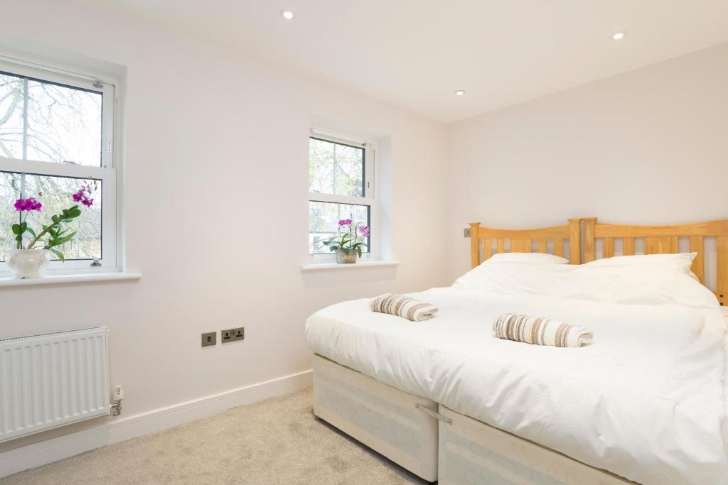 1 dormitorio blanco con 1 cama y 2 ventanas en 7-11 Kings Park en Bicester