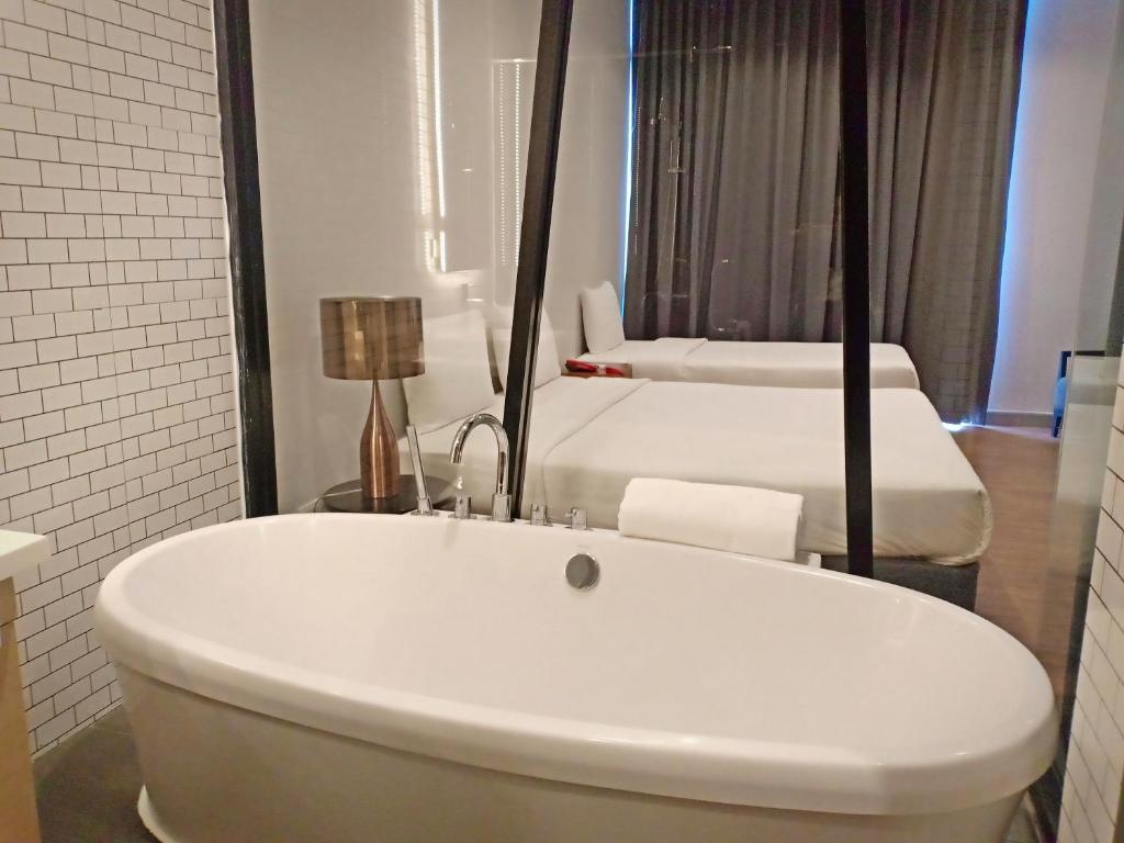 una vasca bianca in un bagno con 2 letti di Vismaya Suvarnabhumi Hotel a Lat Krabang