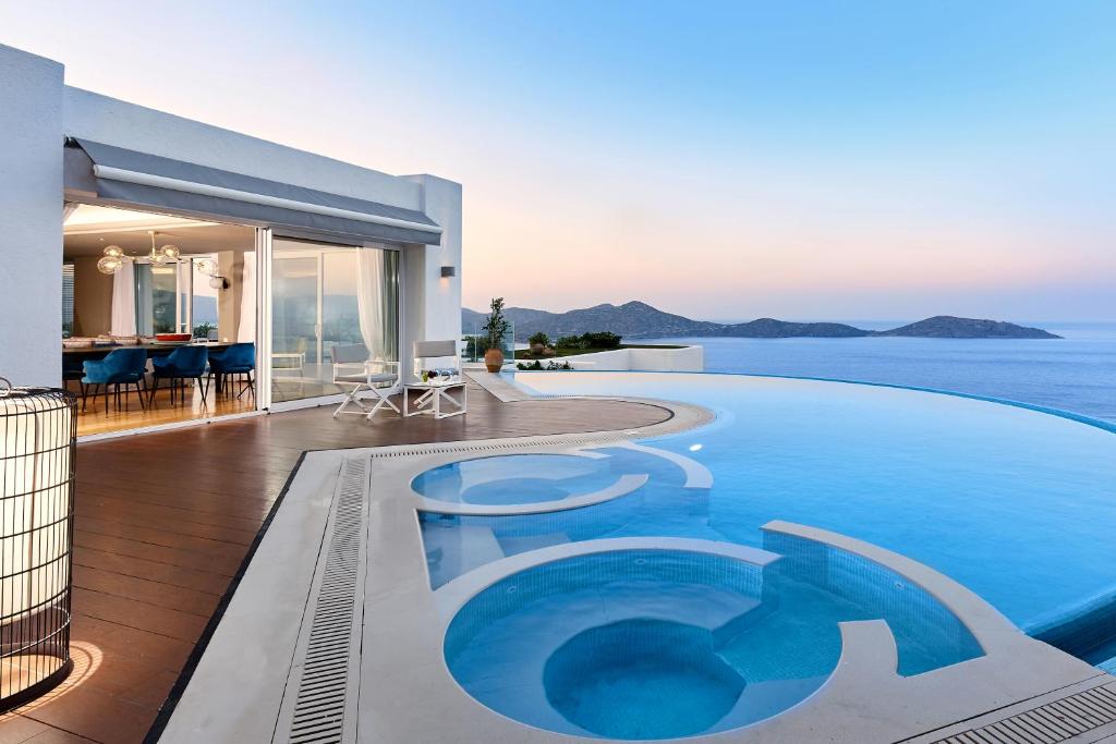 a villa with a swimming pool next to the ocean at Elounda Gulf Villas by Sandglass in Elounda