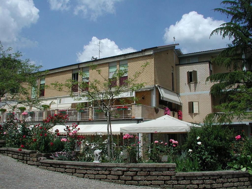 un bâtiment avec un parasol et des fleurs devant lui dans l'établissement Oasi di Pace, à Sutri