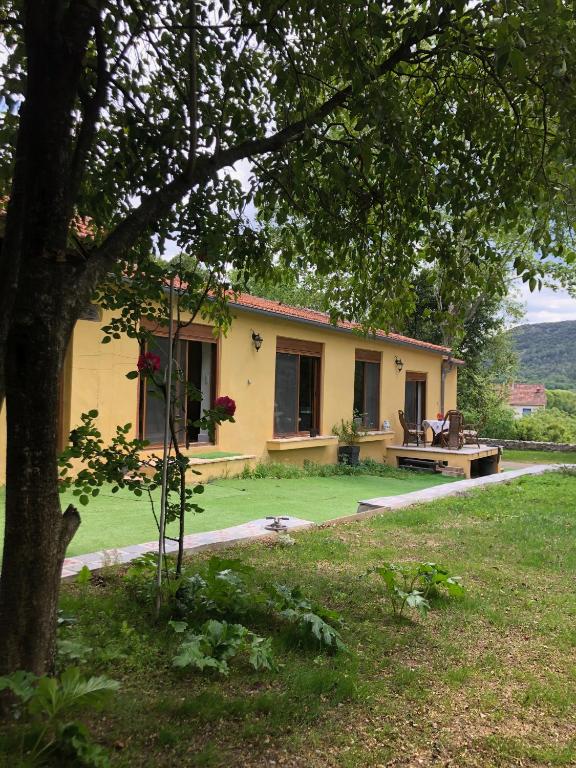 une maison jaune avec un banc dans une cour dans l'établissement Maison dans les Cévennes, à Saint-Hippolyte-du-Fort