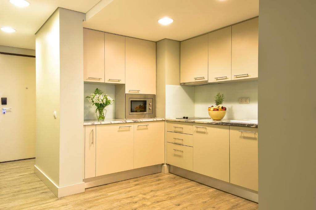a kitchen with white cabinets and wooden floors at Aqualuz Lagos by The Editory in Lagos