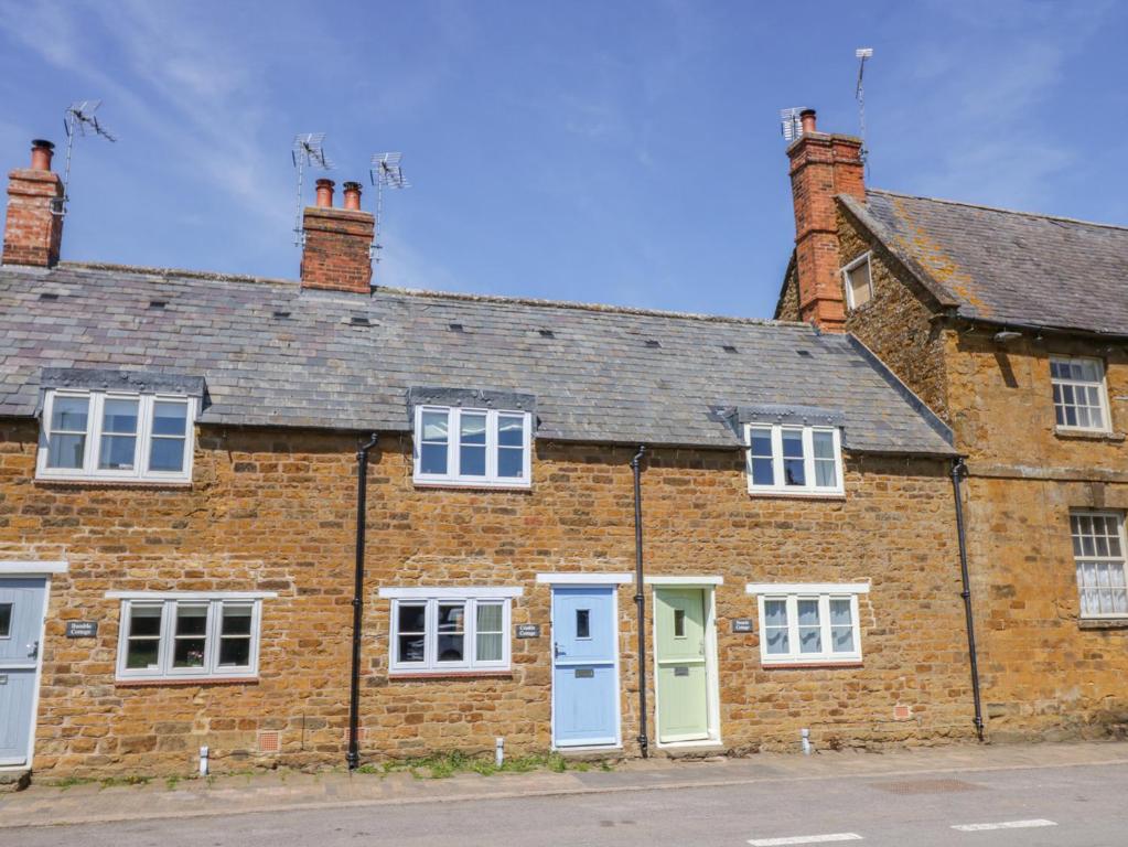 ein altes Backsteinhaus mit weißen Fenstern und Türen in der Unterkunft Treacle Cottage in Warwick