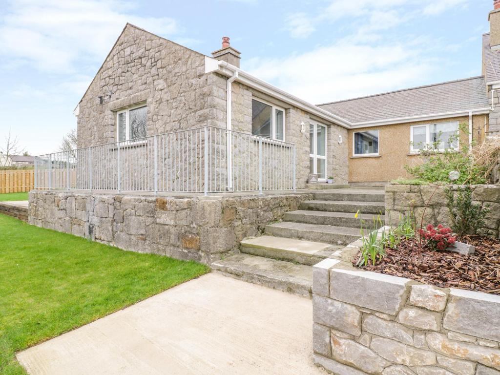 a stone house with a stone retaining wall at Pen Bryn in Llanallgo