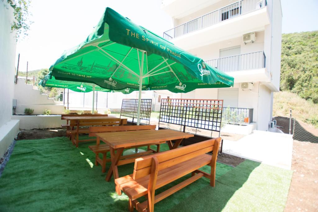 a patio with two wooden tables and a green umbrella at Trsteno Beach Apartments in Budva