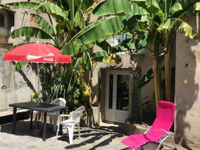 a table and two chairs and a red umbrella at Cévennes Bessegeoises in Bessèges