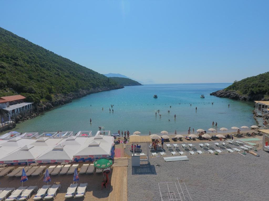 a beach with umbrellas and people in the water at Trsteno Beach Apartments in Budva