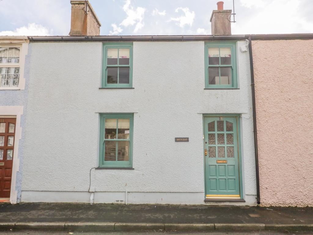 une maison blanche avec des portes et des fenêtres vertes dans l'établissement Bryn Haf, New Street, à Beaumaris