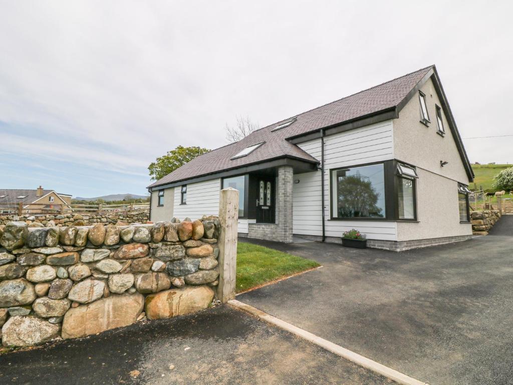 uma cerca de pedra em frente a uma casa em Llwyd Coed Canol em Caernarfon