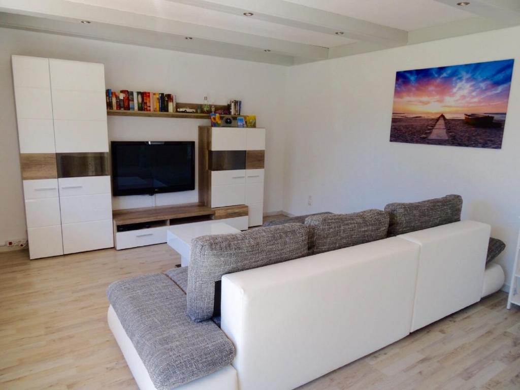 a living room with a white couch and a television at Ferienwohnung Piller 4 Sterne in Michelsneukirchen
