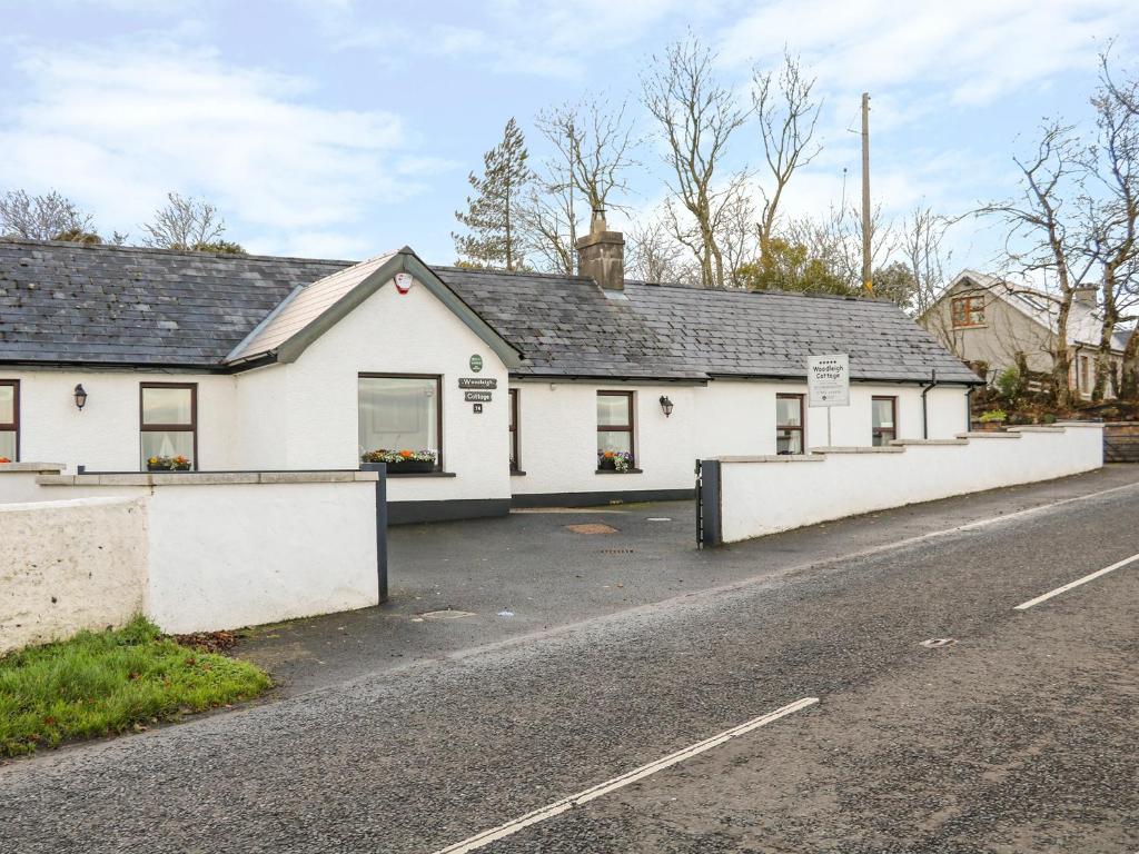 uma casa branca na berma de uma estrada em Woodleigh Cottage em Ballycastle