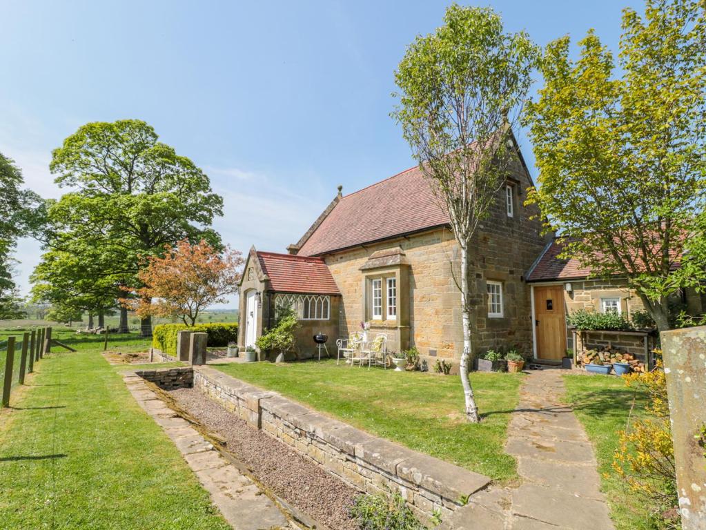 an old stone house with a garden in front of it at Fenwick Retreat at Fenwick Lodge in Newcastle upon Tyne