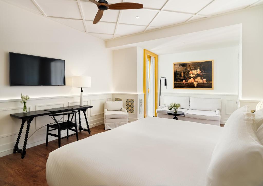 a bedroom with a bed and a desk and a tv at H10 Casa de la Plata in Seville