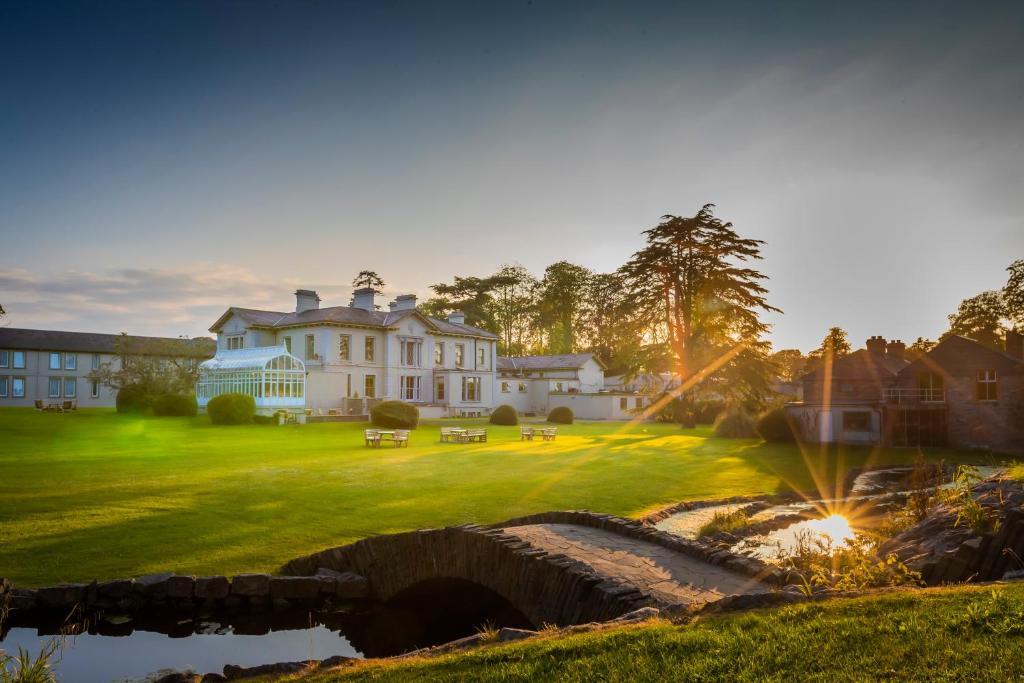 una casa con un puente y un estanque delante en Boyne Valley Hotel - Bed & Breakfast Only, en Drogheda