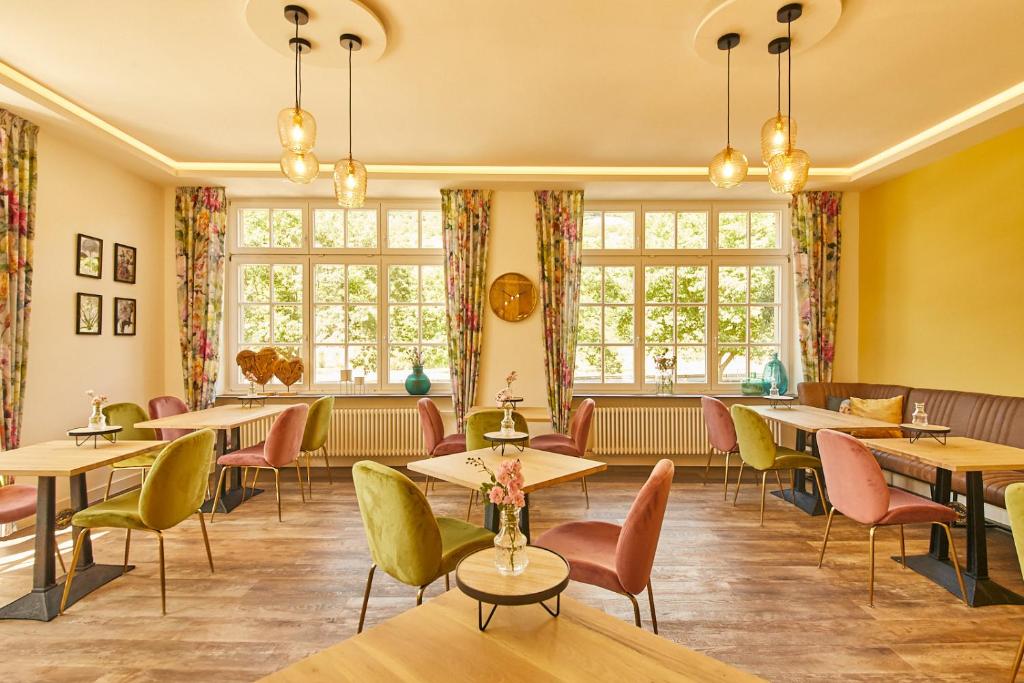 restauracja ze stołami, krzesłami i oknami w obiekcie Rochter Landhotel w mieście Zeltingen-Rachtig