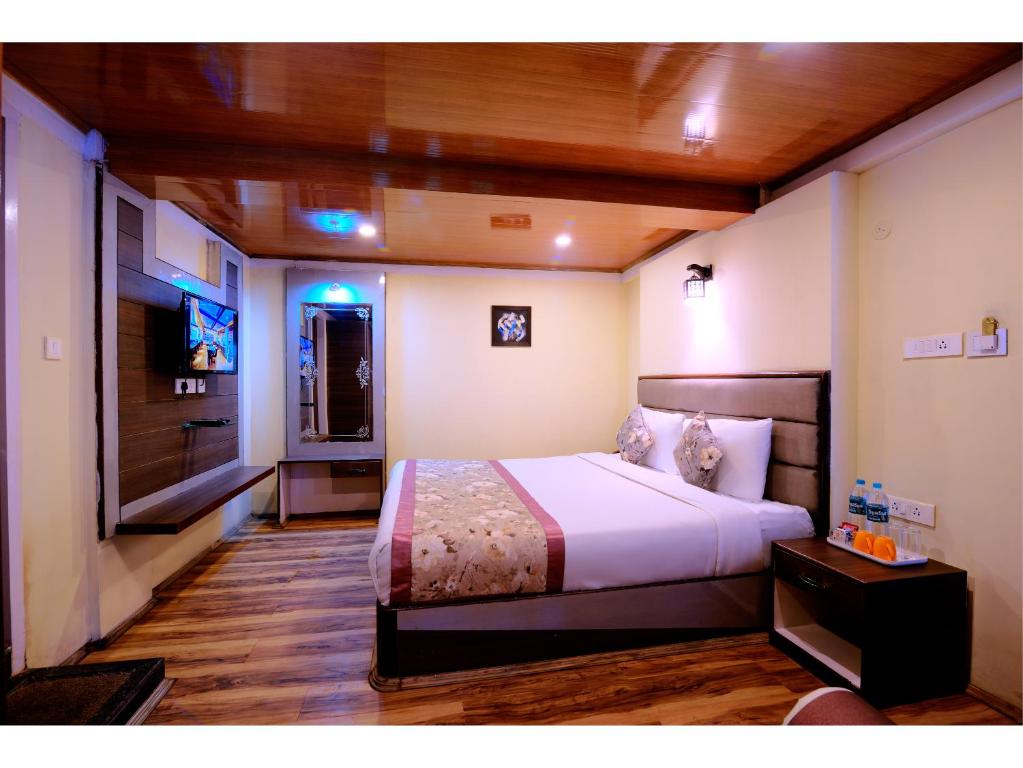 a bedroom with a bed and a flat screen tv at Udaan Olive Hotel & Spa, Pelling in Pelling