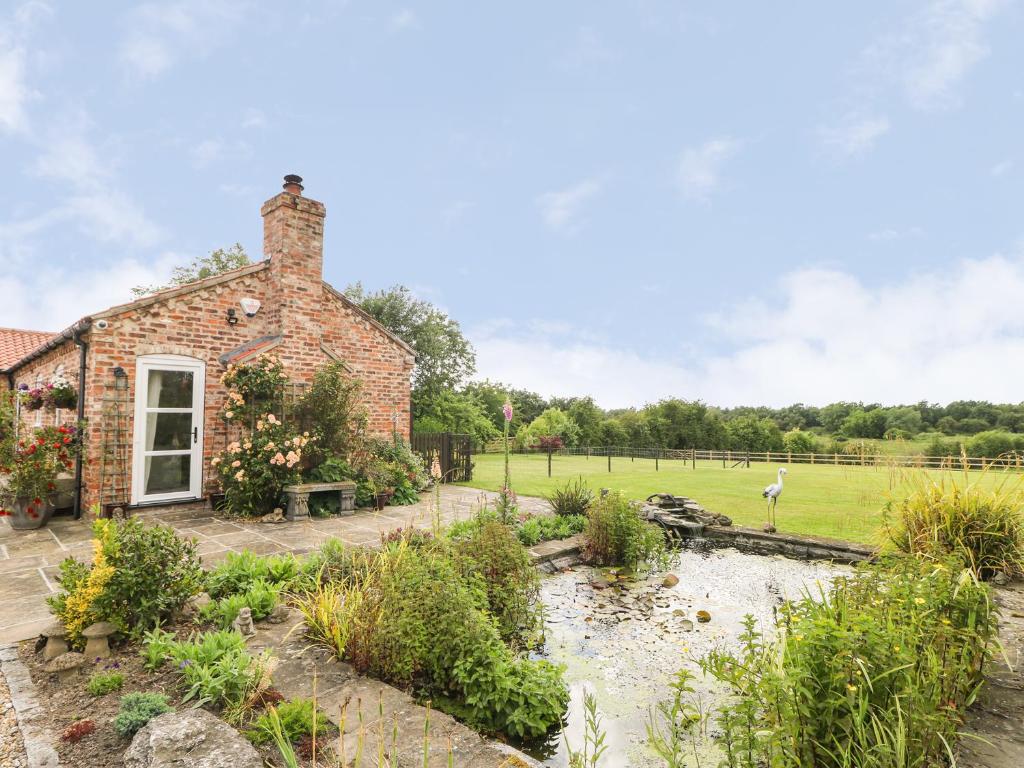 a brick house with a stream in front of it at The Barn at Orchard Farm in York
