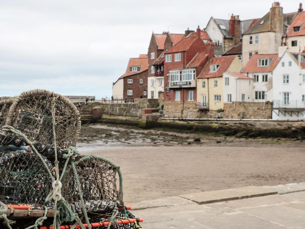 a chair sitting on the beach with houses in the background at Olton Hall Engine Shed in Whitby