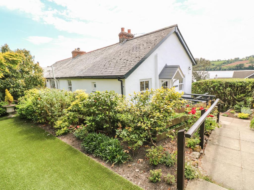 a white house with a garden in front of it at Polsue Cottage in Truro