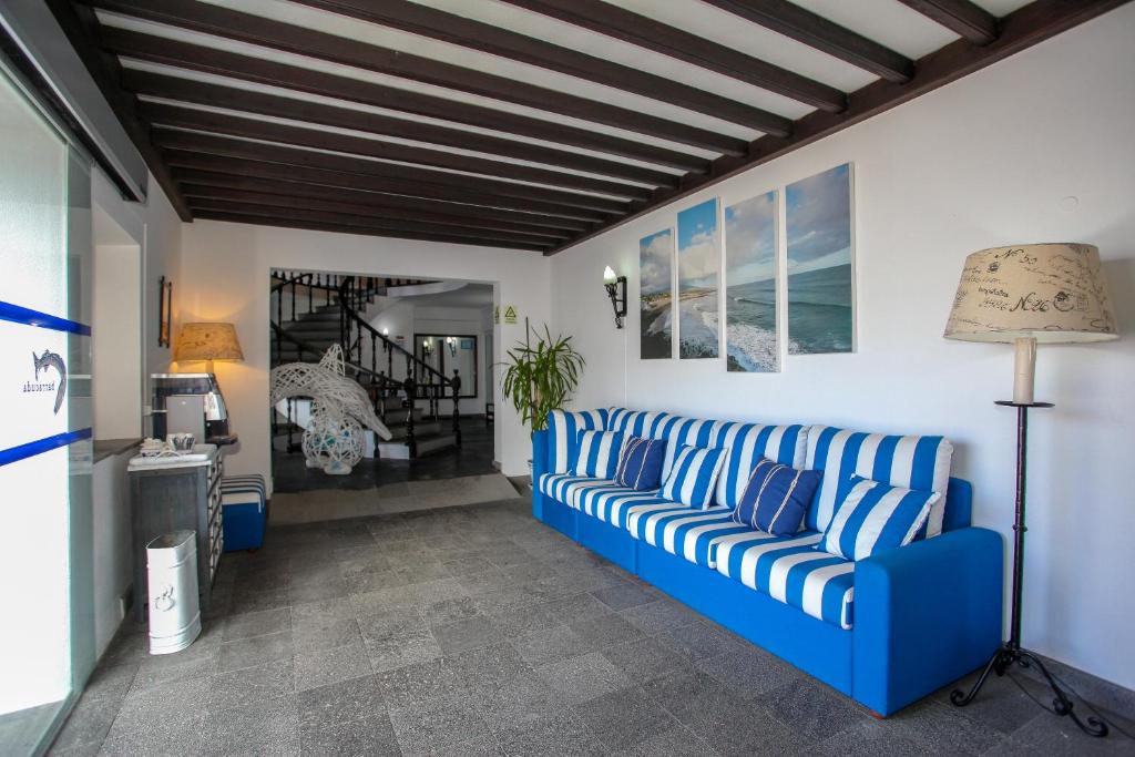 a living room with a blue couch and a staircase at Aparthotel Barracuda in Ponta Delgada